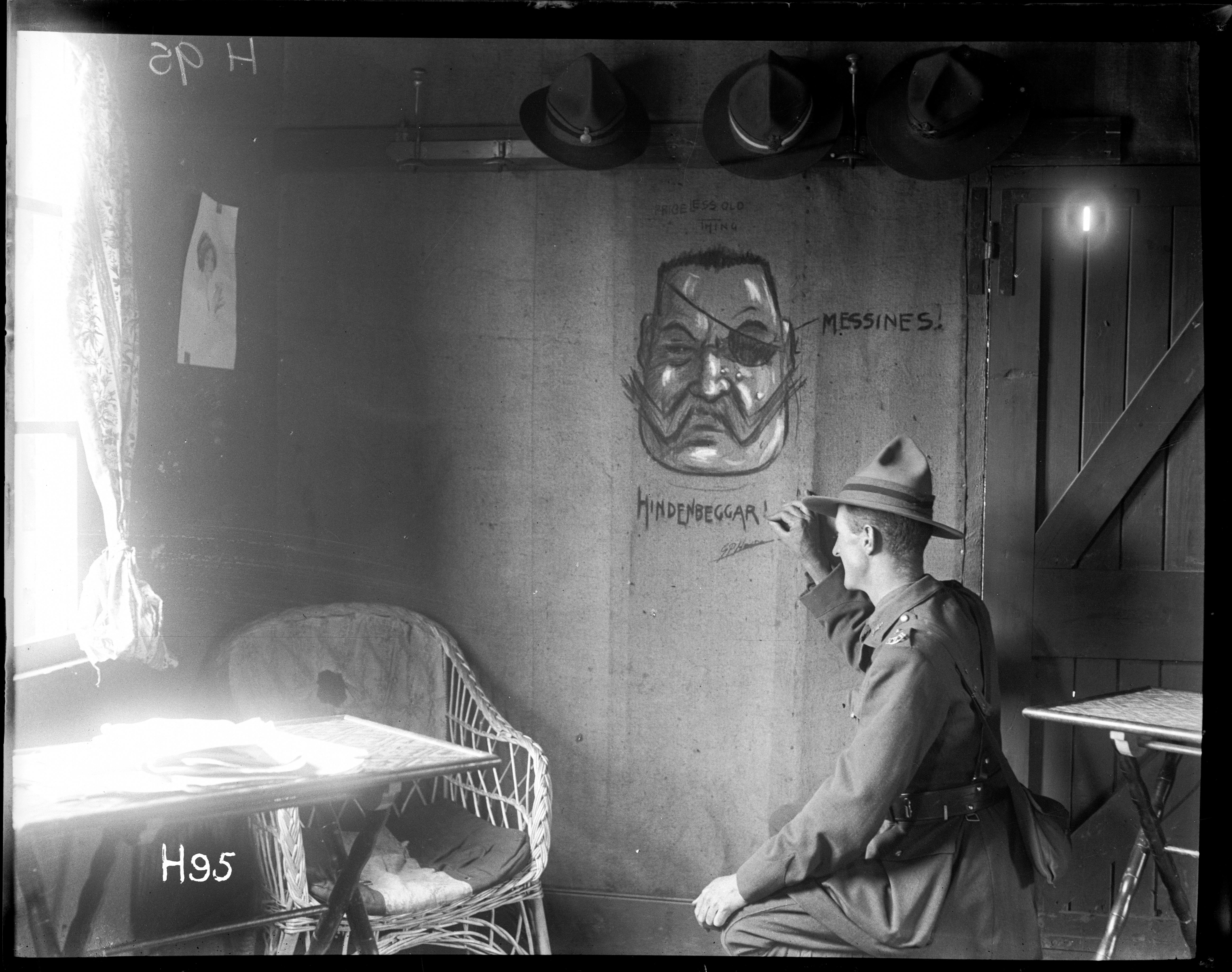 Original photograph: The New Zealand unofficial cartoonist (Lieutenant G. Pat Hanna) enlivens the walls of the officers club