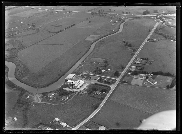 Original photograph: View of the Awanui River, Dairy Factory, Primary School and the Far North Road (State Highway 1F) surrounded by farmland, Northland Region